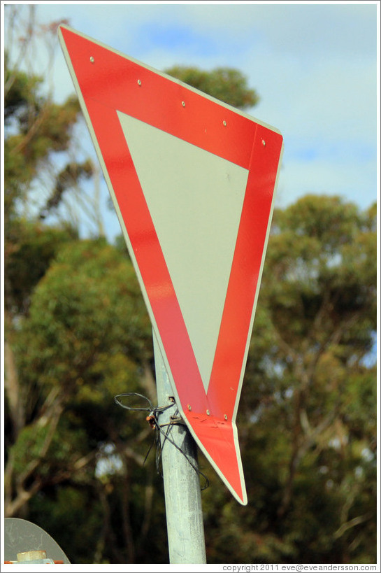 Yield sign with a bent corner. Corner of Slangkop Road and Kommetjie Road, near the Ocean View township.